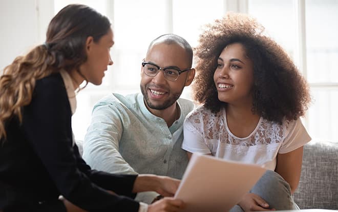 Young African American family couple meeting mixed race agent.