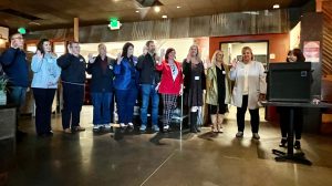 image of a group of people looking on as a person speaks at a podium