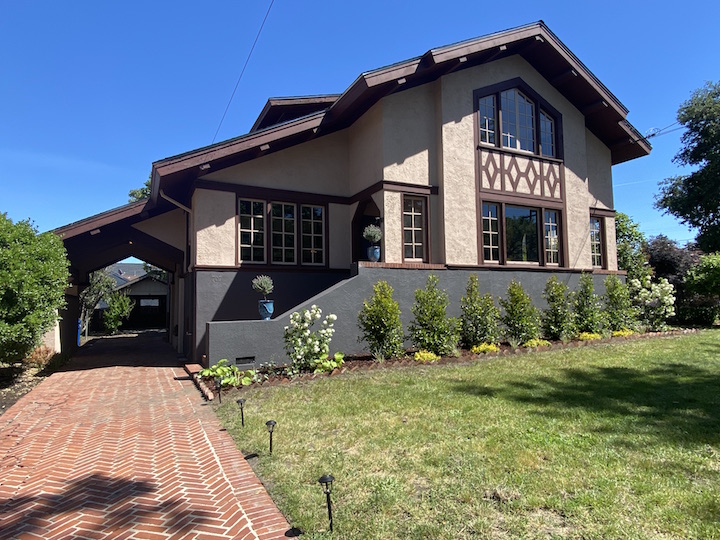 image looking up of large victorian style home with a lush green yard in front.